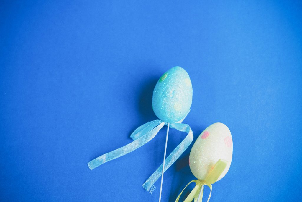 Decorative Easter eggs with ribbons on a vibrant blue background.